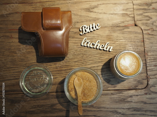 Cappuccino, Zuckerglas, Kamer Tasche und bitte lächeln Zeichen auf Holztisch photo