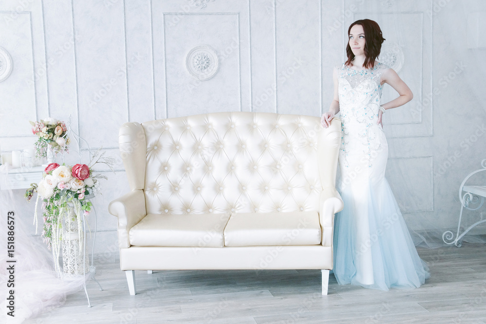 Beautiful young girl in evening dress posing at interior photo studio Beautiful young girl in evening dress posing at interior photo studio