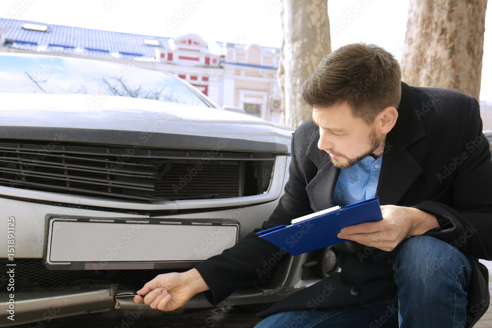 Obraz premium Loss adjuster inspecting car after accident