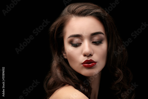 Portrait of beautiful woman with red lips on dark background