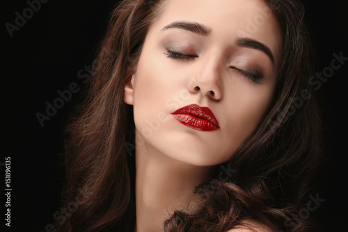 Portrait of beautiful woman with red lips on dark background