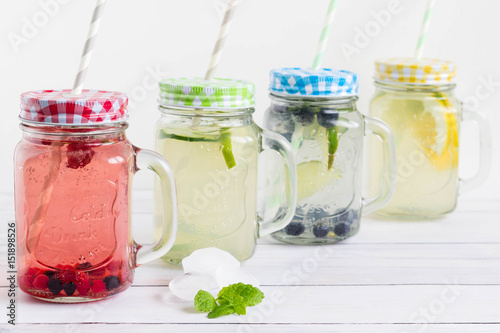 Sugar free and gluten free homemade drinks with trendy mason jars and colorful straws placed on white wooden board.