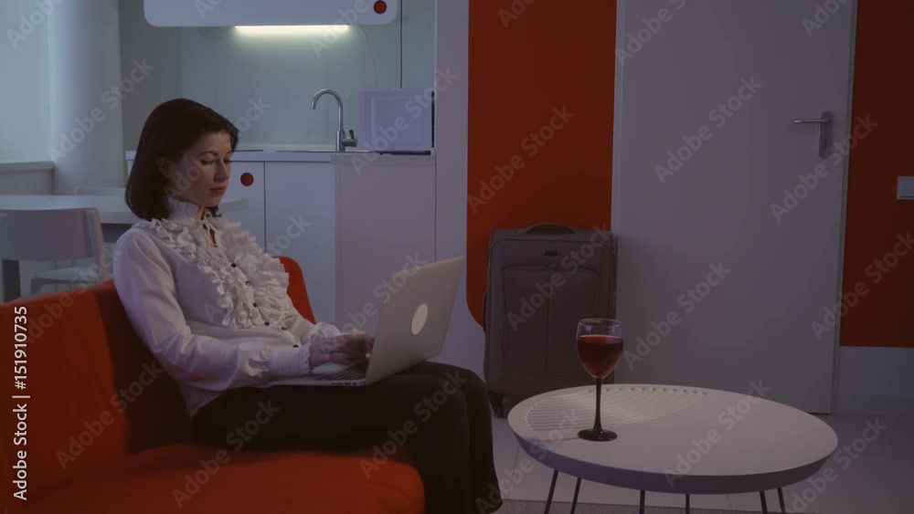 woman resting in apartment in the evening. Young woman chatting online use laptop sitting on the couch indoors. woman resting in apartment in the evening. Young woman chatting online use laptop sitting on the couch indoors.
