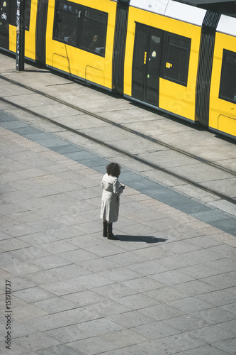 Woman standing alone on the street in front of tramway / tram train
