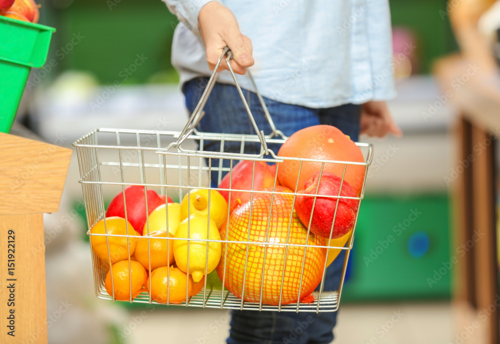 Female hand holding basket with fruits in market