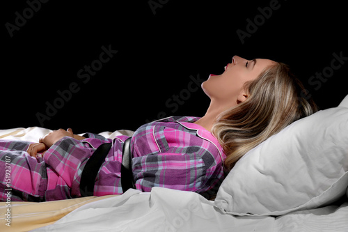 Screaming girl tied with belt in bed. Sleep paralysis concept photo