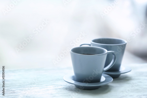 Cups with hot tea on wooden table against blurred background © Africa Studio