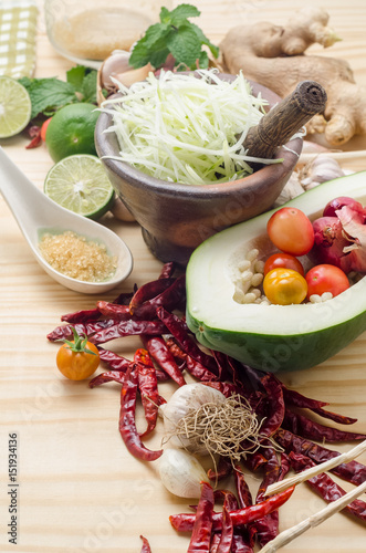 Ingredients for making papaya salad on a wooden table. Set of Thai spices and herbs