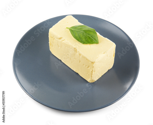 Plate with butter and basil leaf on white background, closeup