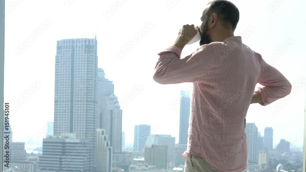 Young man drinking coffee and admire view form window in apartment
Young man drinking coffee and admire view form window in apartment
