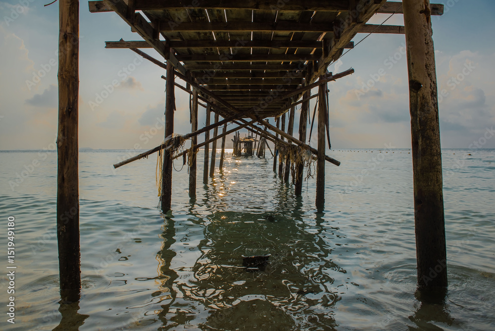Old wooden bridge in the sea at morning time .
