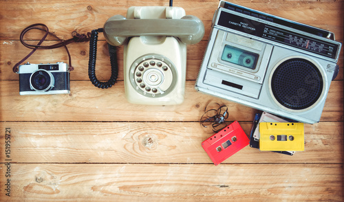 Top view hero header - retro technology of radio cassette recorder with retro tape cassette, vintage telephone and film camera on wood table. Vintage color effect styles. photo