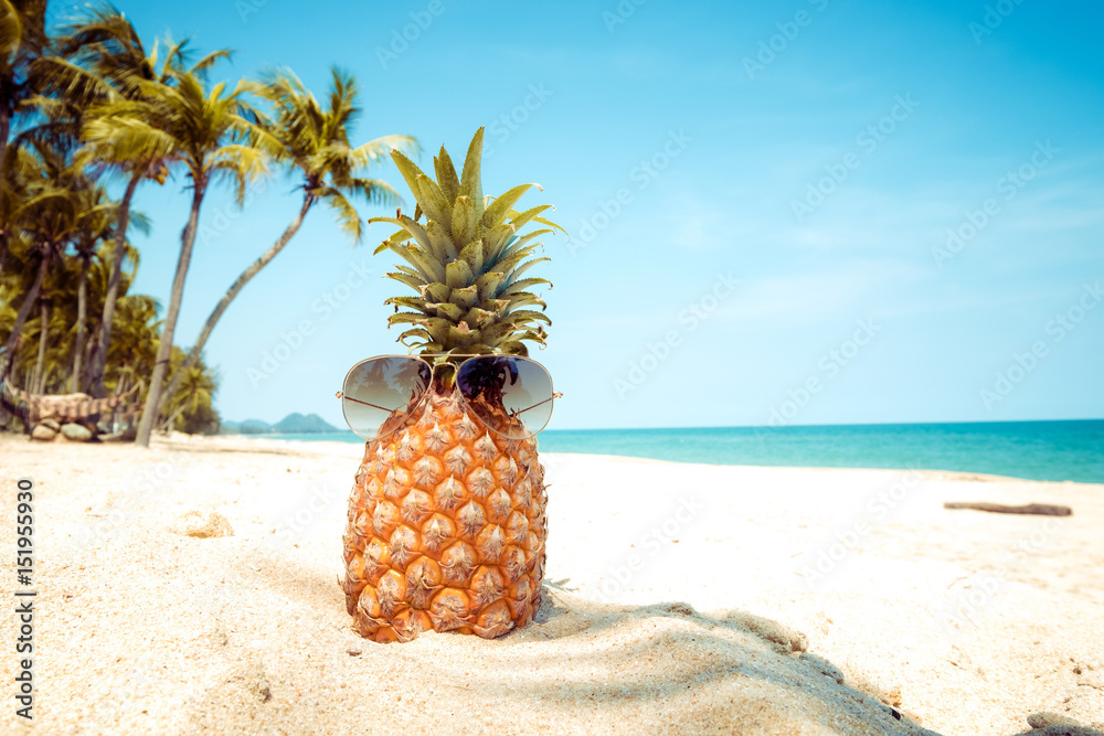 Hipster pineapple with sunglasses on a sandy beach with palm tree. concept of fashion in summer. vintage colortone filter effect Hipster pineapple with sunglasses on a sandy beach with palm tree. concept of fashion in summer. vintage colortone filter effect