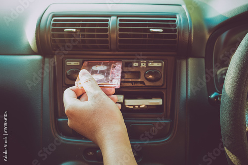 Woman hand holding tape cassette in car for driving listen music - vintage color tone effect. photo