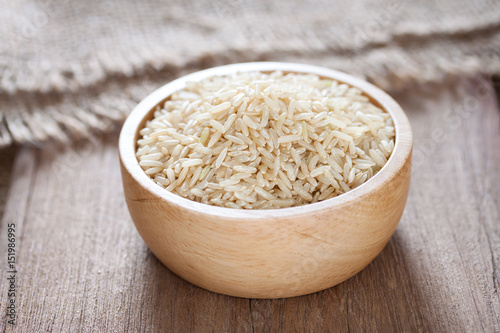 Brown rice in a bowl on wooden texture and table