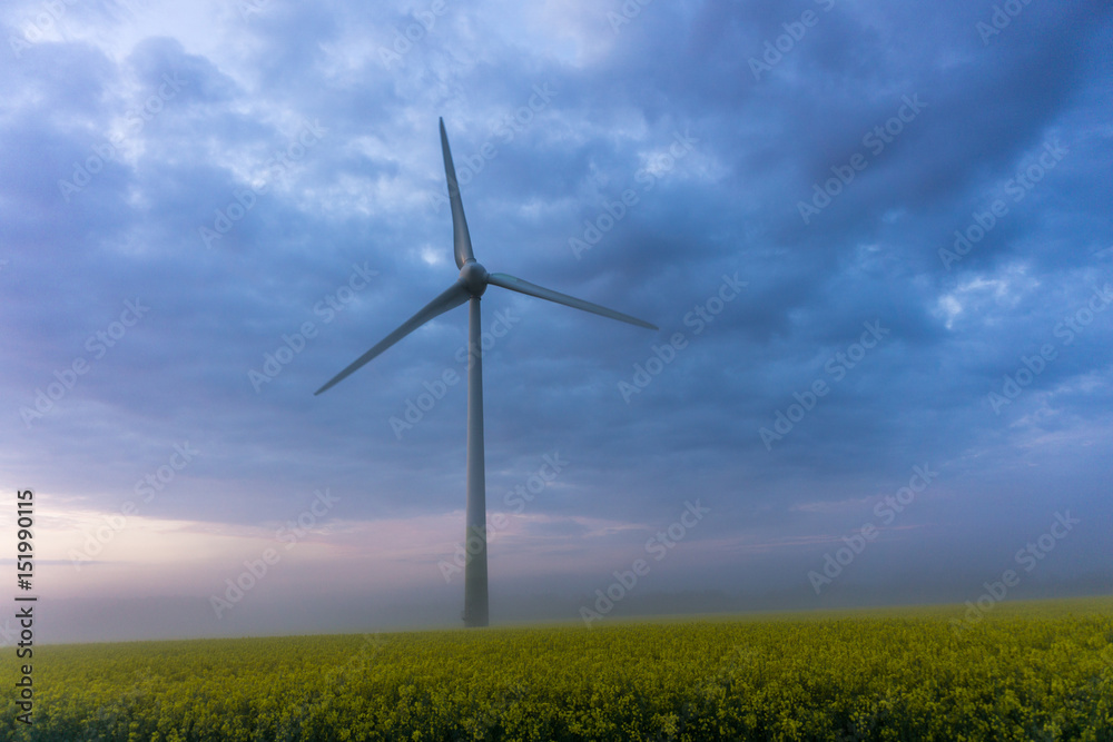 wind wheels at sunrise and fog with dark clouds
