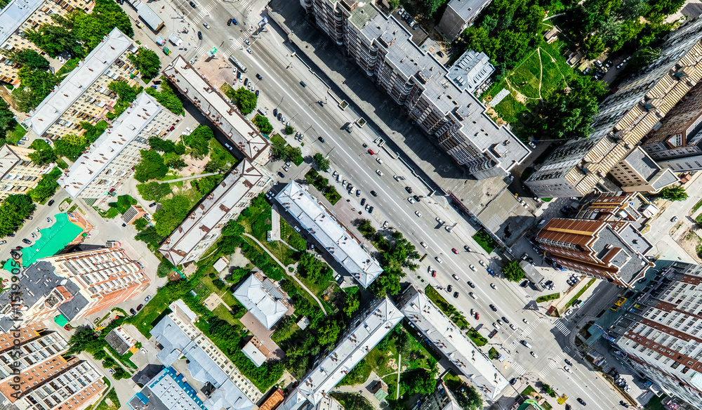 Fototapeta premium Aerial city view with crossroads and roads, houses, buildings, parks and parking lots, bridges. Helicopter drone shot. Wide Panoramic image.