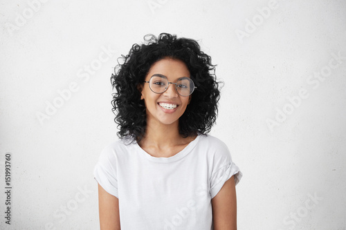 Принти на полотні Pretty female with dark skin and broad happy smile wearing big round eyeglasses