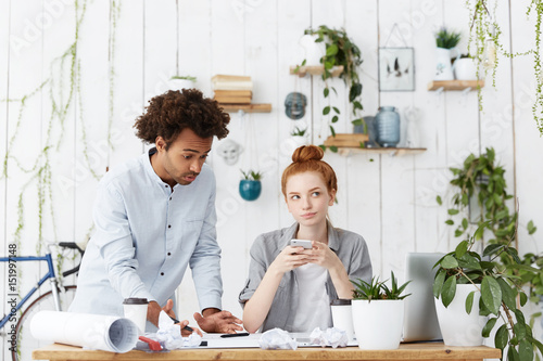 Vászonkép Chief male engineer feeling annoyed with his clueless woman trainee who is using mobile during work, ignoring him