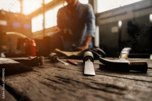 Fotografie Vintage tone of equipment on wooden desk with man working in workshop background
