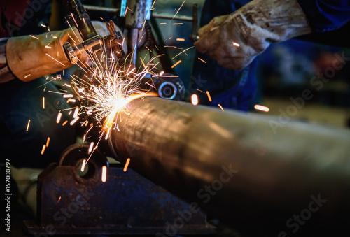 фотографія Worker cutting steel pipe with acetylene welding cutting torch and bright sparks in steel construction industry