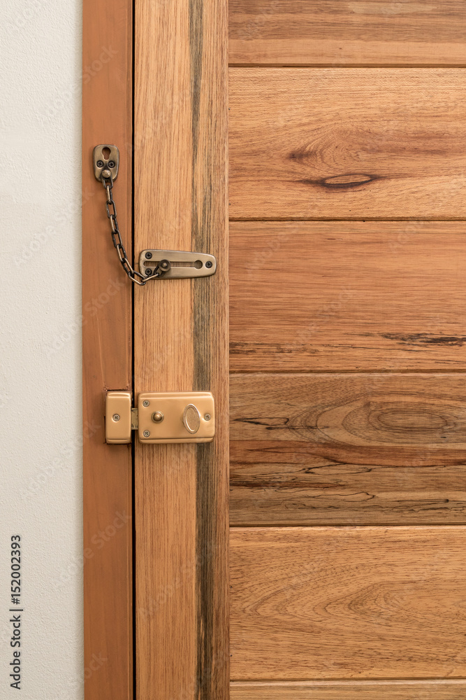 hotel door lock system and slide chain lock on stylish wooden door, view from inside the room, security system concept hotel door lock system and slide chain lock on stylish wooden door, view from inside the room, security system concept