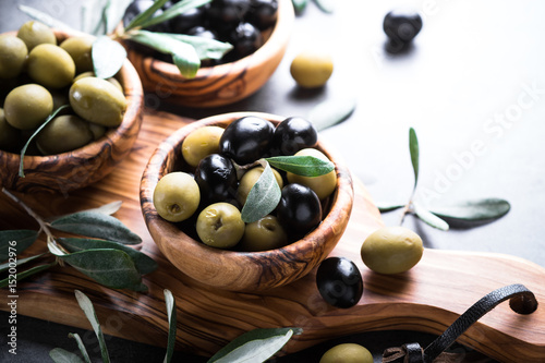 Black and green olives in wooden bowl