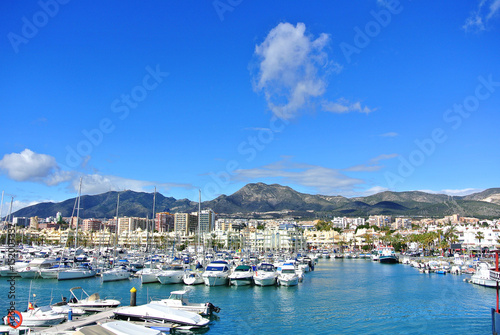 BENALMADENA, SPAIN - FEBRUARY 13, 2014: Benalmadena Marina port, a view to piers with yachts, Mediterranean sea and mountains at the background.