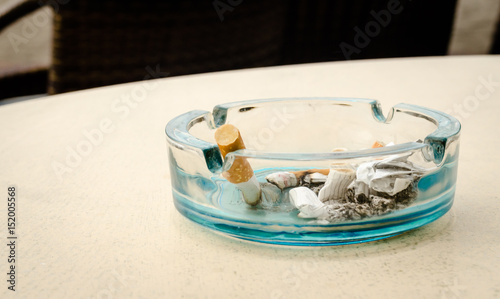 Ashtray with cigarette butts on the table.