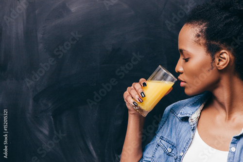 Young african woman drink glass of orange juice. Healthy life, detox vitamin diet, vegetarian concept.