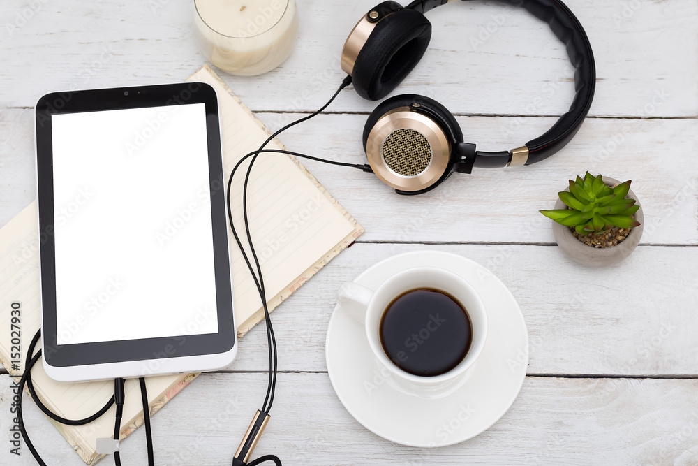 Cozy home still life. Tablet, cup and golden headphones on a white wooden background Cozy home still life. Tablet, cup and golden headphones on a white wooden background