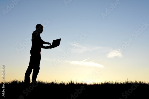 Man on his computer in silhouette