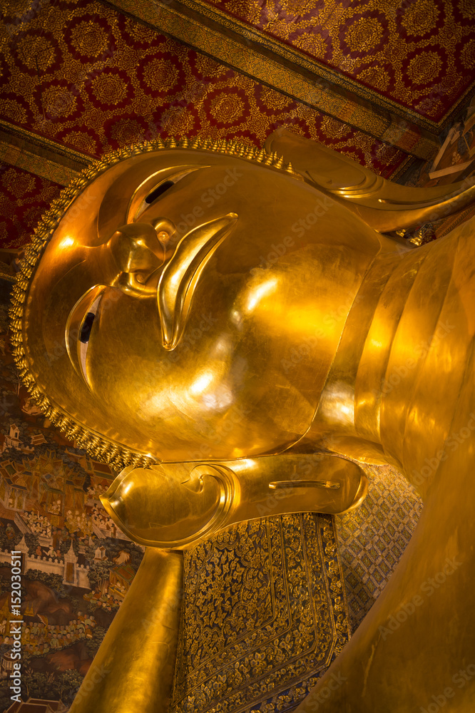 Close-up of the giant golden face of a Buddha in reclining pose