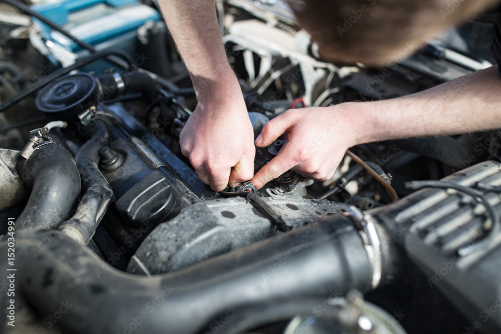 The master repairs under the hood of the car The master repairs under the hood of the car