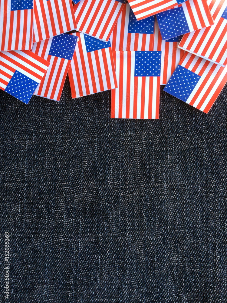 Obraz premium Miniature paper flags of the United States of America on a blue denim material background with copy space