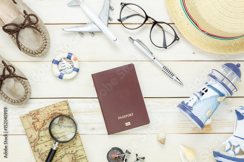 Top view accessories to travel beach.The woman shoes notebook map passport airplane boat music eyeglasses on white wooden background.