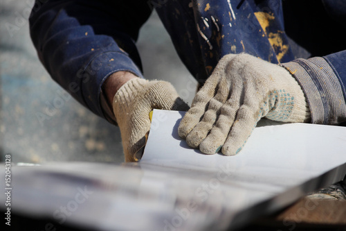 The worker makes the sladding of windows in the restored building in the city, cuts the metal sheet for the slope with scissors. photo