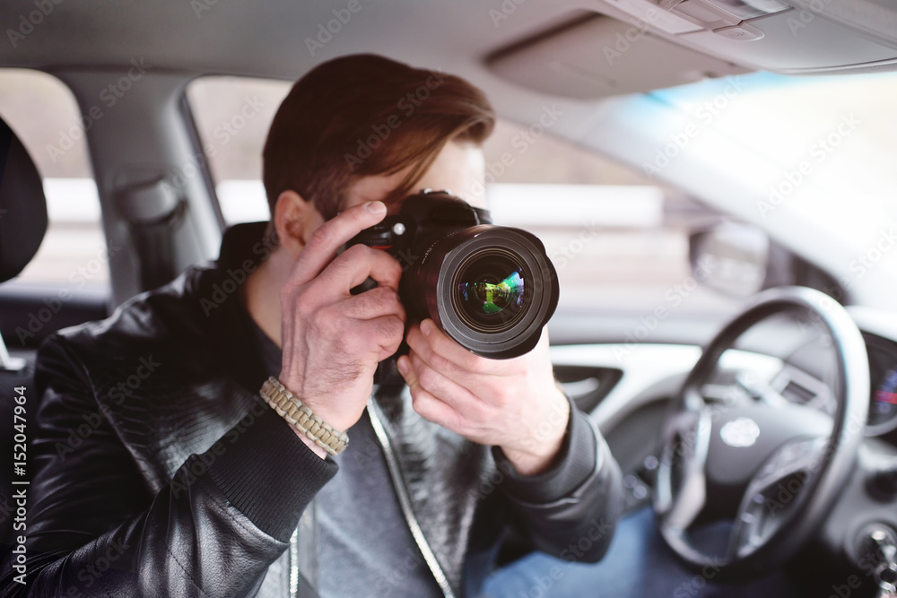 The man in the car reviews the photos on the camera. Spy, paparazzi, journalist, photographer. The man in the car reviews the photos on the camera. Spy, paparazzi, journalist, photographer.