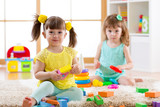 Little kids playing with colorful toys on the floor at home or kindergarten. Educational games for children.