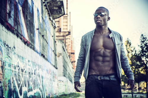 Portrait of a hot black man in sunglasses with visible abs posing for camera © theartofphoto