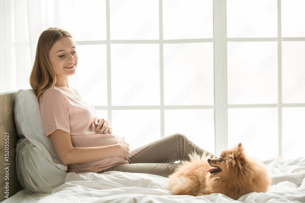 Young preganant woman expecting a baby relaxing on bed indoors