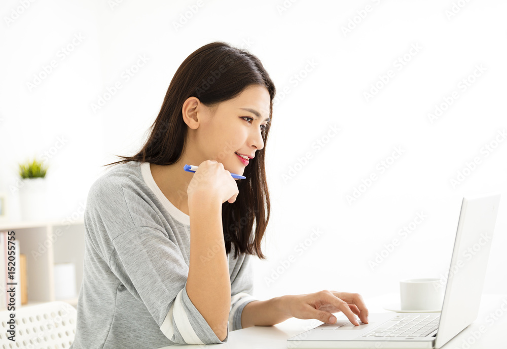beautiful young woman smiling and looking at laptop . beautiful young woman smiling and looking at laptop .