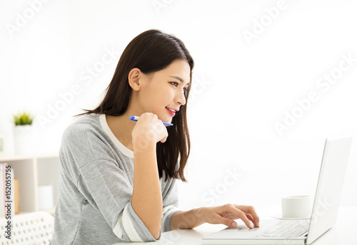 beautiful young woman smiling and looking at laptop .