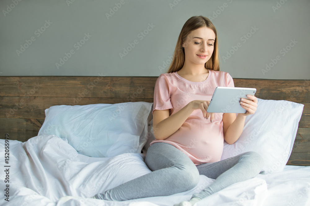 Young preganant woman expecting a baby relaxing on bed indoors Young preganant woman expecting a baby relaxing on bed indoors
