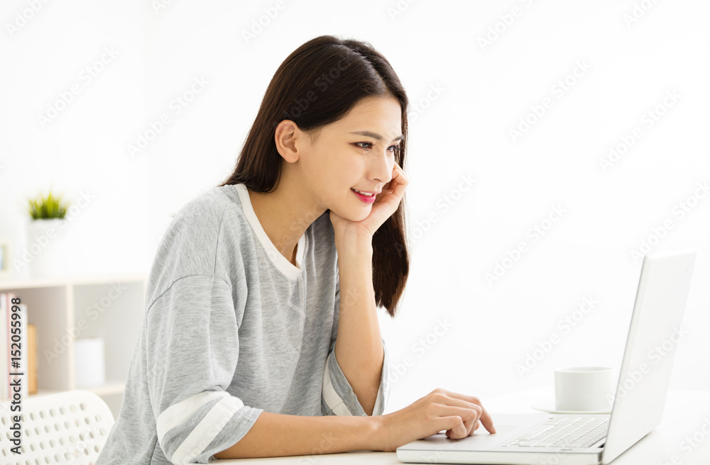 beautiful young woman smiling and looking at laptop . beautiful young woman smiling and looking at laptop .