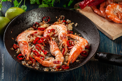 Shrimps roasted on frying pan with onion, garlic and chili