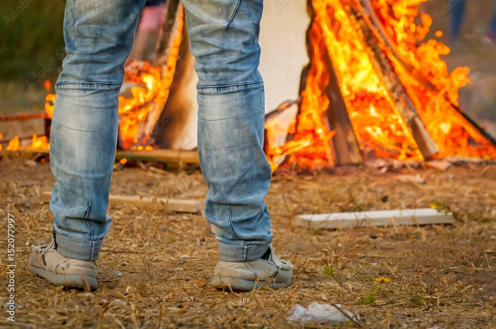 Man in blue jeans looking at the burning bonfire stock image. Man in blue jeans looking at the burning bonfire stock image.