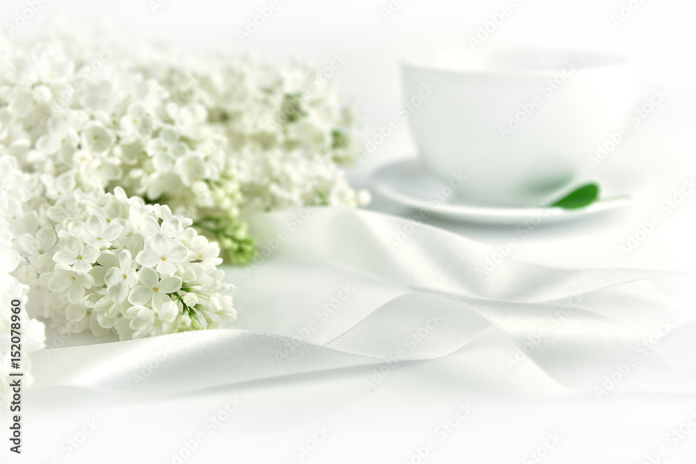 White lilac with ribbon and cup of tea at the morning