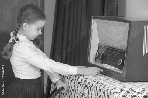 Little girl listens to old radio.