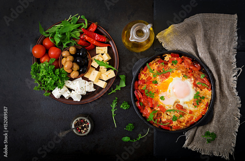 Breakfast. Fried eggs with vegetables - shakshuka in a frying pan on a black background in the Turkish style. Flat lay. Top view